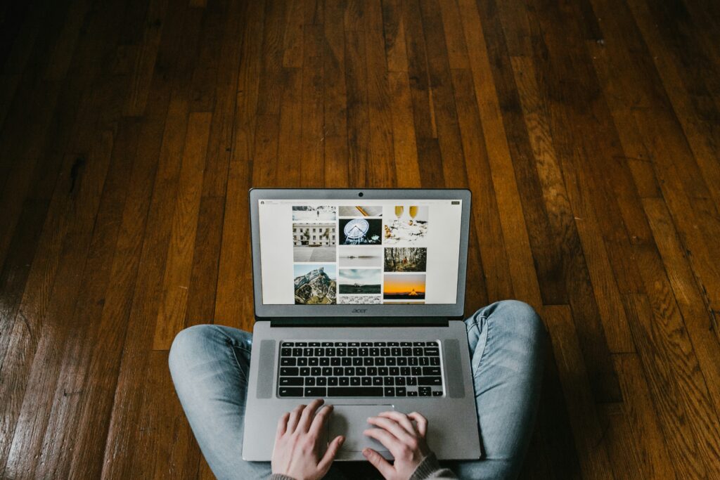 Man sits on wood floor with his laptop on legs